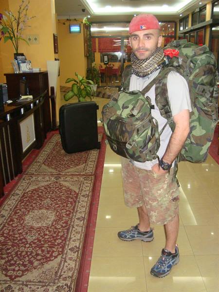 Traveler with camouflage backpacks and keffiyeh scarf in a hotel lobby
