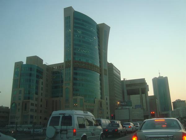 City traffic in front of blue glass skyscrapers at dusk
