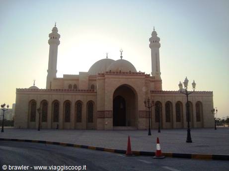 Large beige mosque with dome and two minarets, empty courtyard in morning light