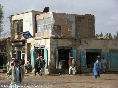 Dirt street with shopkeepers in tunics outside mud-brick shops, daytime light