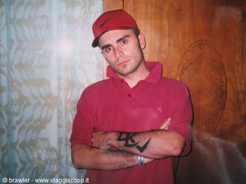 Man in red Nike cap and red polo shirt, arms crossed, next to wooden wardrobe
