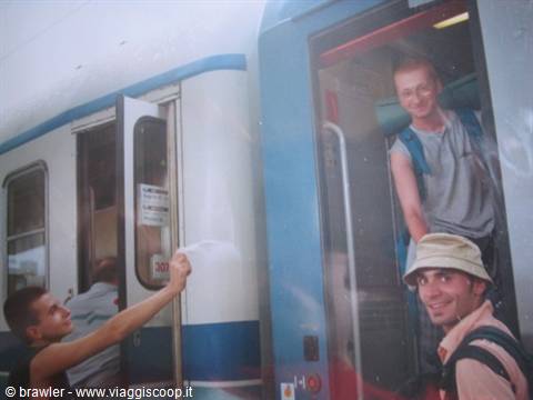 Two backpackers boarding a blue and white train at the station