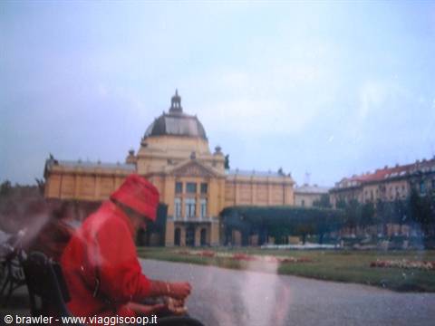 Woman in red on bench before the Zagreb Art Pavilion