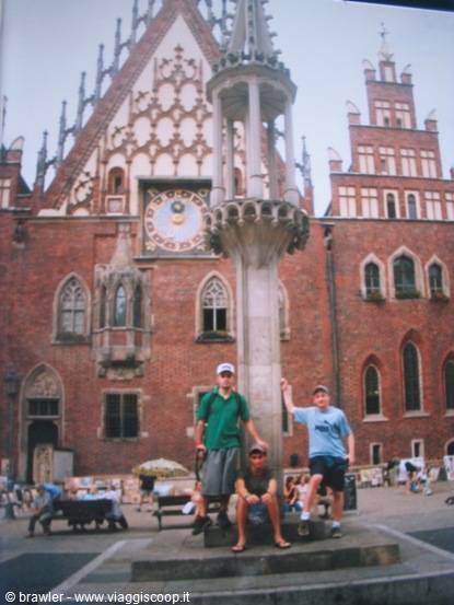 Three boys beside a Gothic column in front of Wrocław town hall