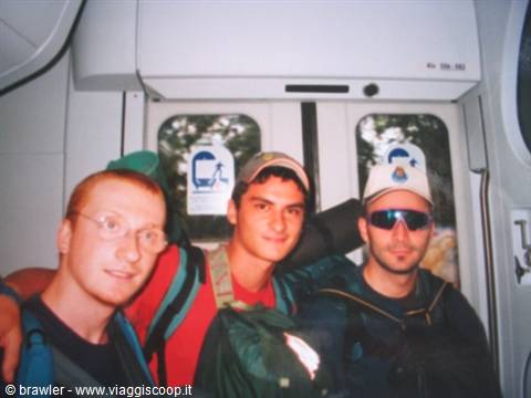 Three young backpackers with caps inside a train carriage