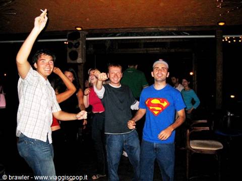 Young guys dancing in a dark club, one wearing a Superman shirt