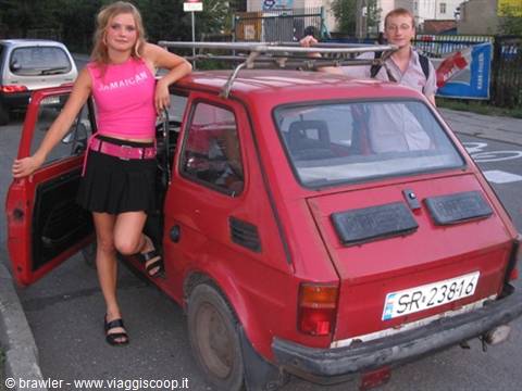 Girl in pink top next to a red Fiat 126p parked on a street