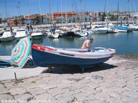 Man tending a fishing boat on the quay, sailboats moored behind