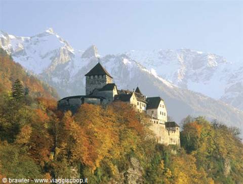 Vaduz Castle among autumn trees with snowy mountains behind