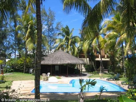 Pool with thatched gazebo among palm trees, sun loungers in tropical garden