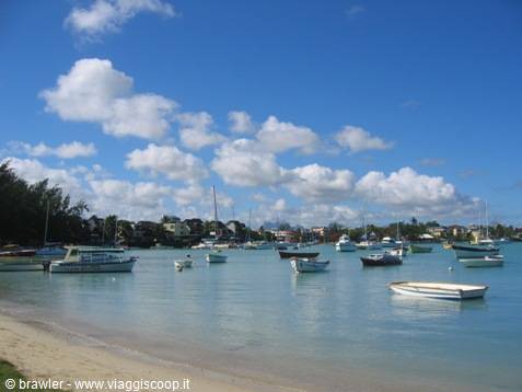 Boats anchored in a tropical bay with white sand and cloudy sky