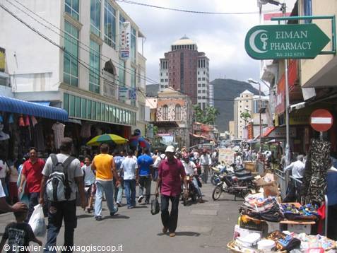 Crowded street in Port Louis, green Eiman Pharmacy sign, skyscraper in background