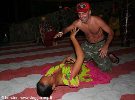Dancers in yellow and pink costumes perform on mosaic floor under night lights