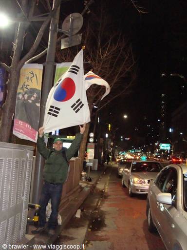 Man waving a South Korean flag on a night street in Seoul