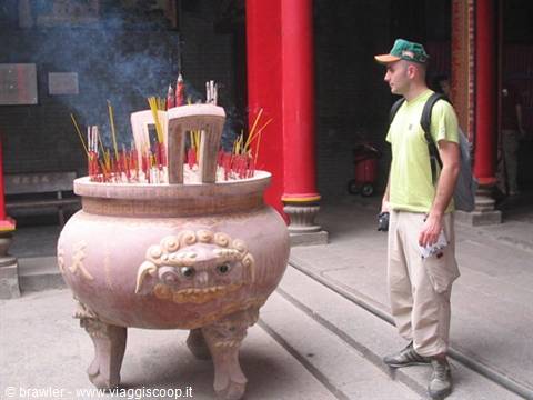 Tourist beside a large stone incense burner with smoking incense sticks at a temple
