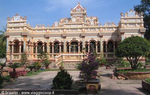 Ornate facade of Vinh Trang Pagoda, ceramic decorations, sunny garden