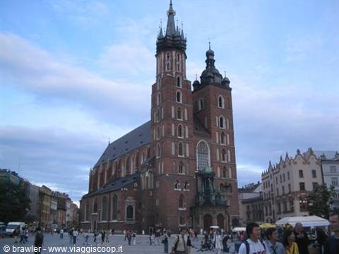 Tourists stroll across the square before the gothic brick St. Mary's Basilica in Kraków