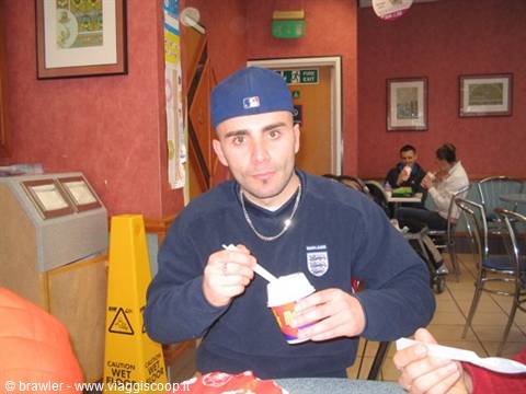 Young man in blue Dodgers cap eats an ice cream cup in a café