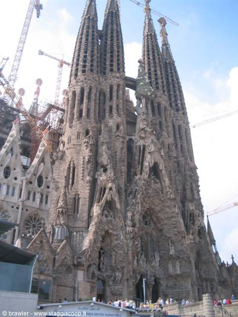 Tourists in front of the Sagrada Familia facade, cranes among the stone spires