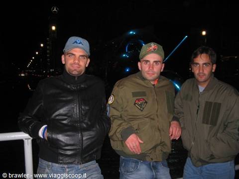 Three friends posing at night by a river, leather and military jackets, streetlights