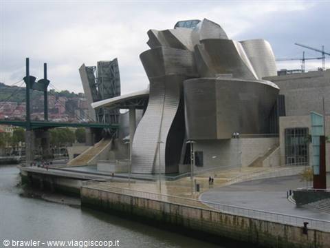 Guggenheim Museum Bilbao, curving titanium panels under grey sky, river and pedestrians