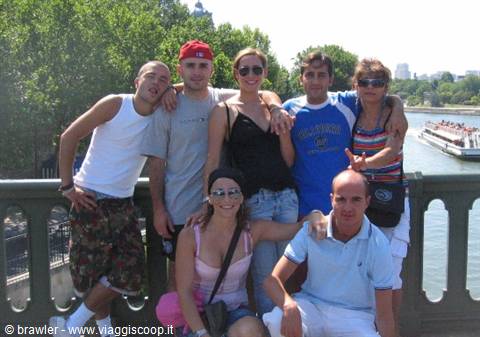 Group of friends posing on a bridge, a river boat behind them