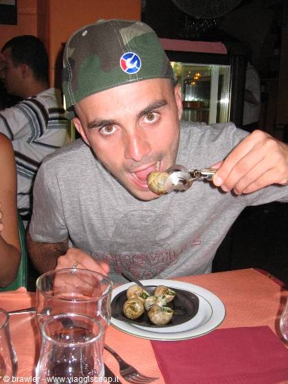 Young man in camo cap eating an escargot with a snail tong