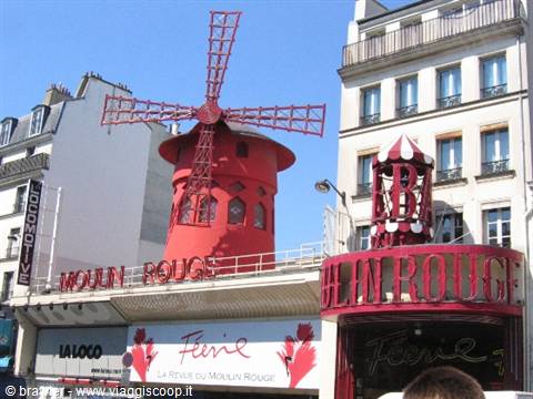 The red windmill of the Moulin Rouge in Pigalle, Paris, under blue sky