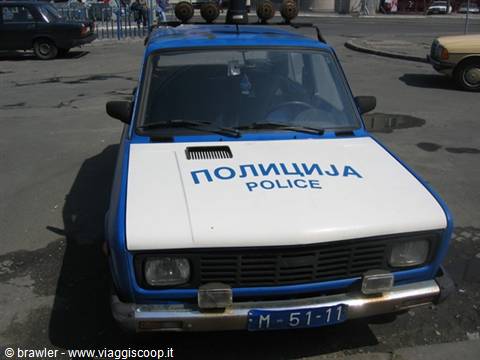 Blue and white police car with Cyrillic lettering parked on the street