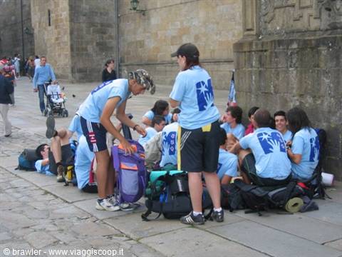 Young pilgrims in blue shirts rest with backpacks on a stone square, Santiago de Compostela