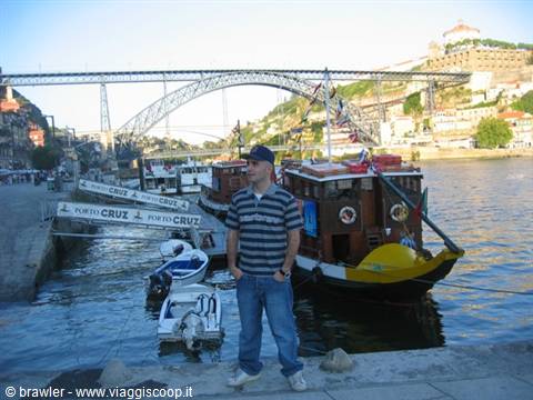 Man in jeans beside traditional rabelo boats on the Douro, Dom Luís I bridge