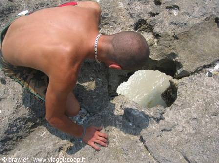 Man leaning over limestone rock with white foam pool