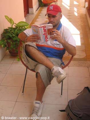 Tourist in red cap reading a Lonely Planet guide on a red patio chair
