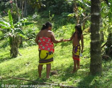 Woman and girl in sarongs exchanging an item in tropical woods