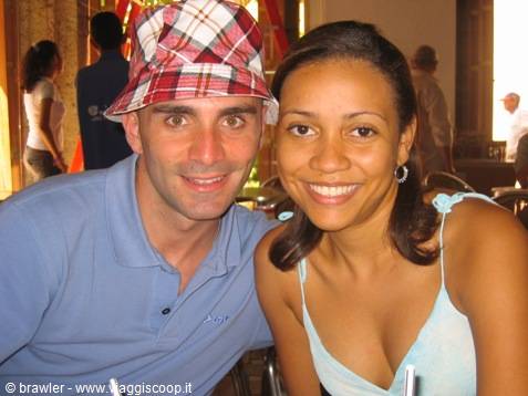 Man in plaid hat and smiling woman posing in a crowded indoor café