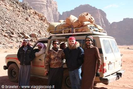 Tourist with Bedouin guides beside a loaded jeep among Wadi Rum rocks