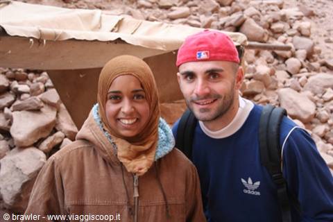 Backpacker and smiling woman in headscarf among piles of desert rocks