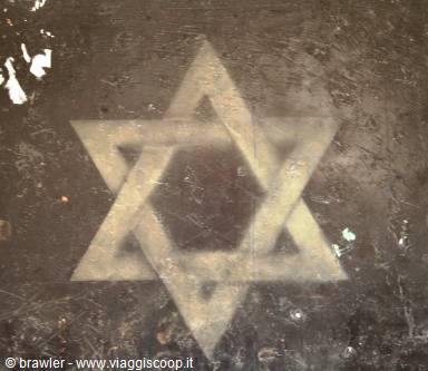 Star of David stenciled in white on a rusty wall, soft light