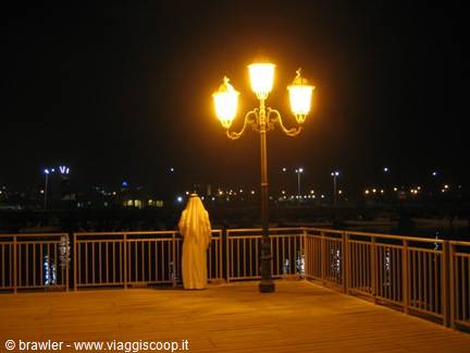Man in white thobe on a lit bridge at night, Abu Dhabi