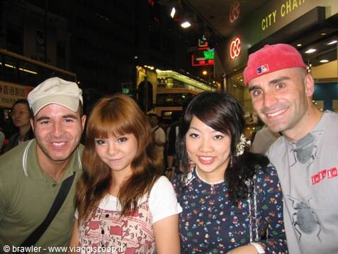 Four smiling friends at night in Hong Kong, neon signs and city traffic