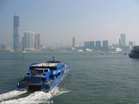Blue ferry crosses Victoria Harbour with skyscrapers in the haze