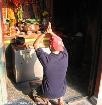 Man praying before a Buddhist altar with incense and offerings