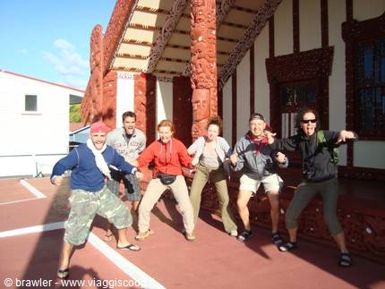 Tourists striking a haka pose before Waitangi's carved wooden meeting house