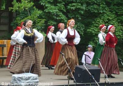 Dancers in striped skirts and red headscarves performing on an outdoor stage