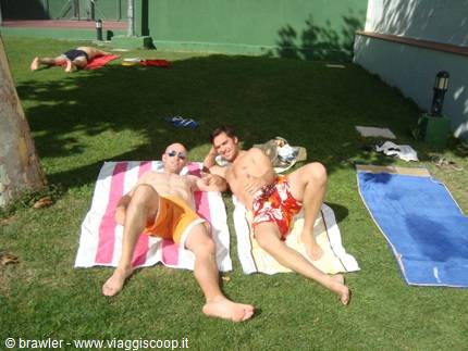 Two guys sunbathing on colorful towels on a green lawn
