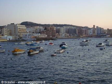 Leisure boats moored in the harbour in front of coastal buildings at dusk