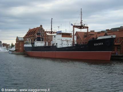 Museum ship Sołdek moored beside brick warehouses in Gdańsk