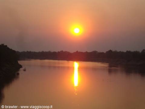Low sun reflecting on a calm river lined with trees