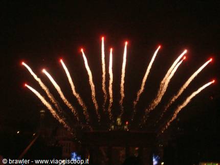 Red and golden fireworks fan out across the night sky above Brandenburg Gate