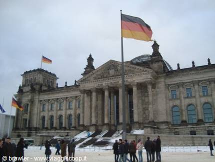 German flag waving in front of the Reichstag, tourists on the snow in Berlin